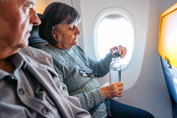 istock Senior Woman Drinking Water While Riding In An Airplane 2199136548