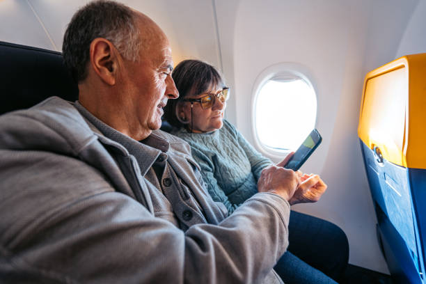 istock Senior Couple Using A Phone Together While Riding In An Airplane 2199136697