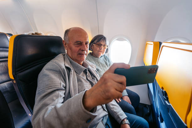 istock Senior Couple Taking Selfies Using A Phone While Riding In An Airplane 2199136764
