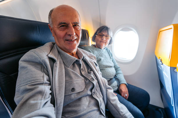 Senior Couple Taking Selfies While Riding In An Airplane