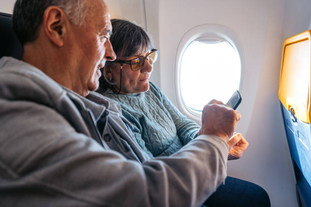 istock Senior Couple Using A Phone Together While Riding In An Airplane 2199136925