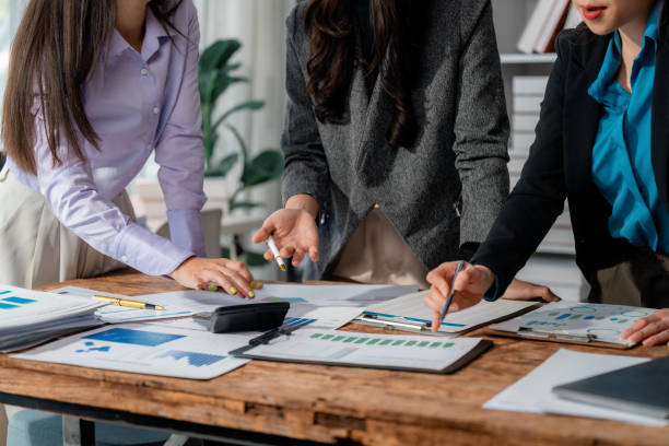 istock Professional businesswomen reviewing financial documents, analyzing market data, strategizing company growth while working closely in modern office setting 2199137106
