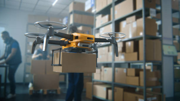 istock Logistics Distribution Center: UAV Drone Carrying Cardboard Box, Workers Managing Inventory 2199138567