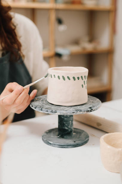 istock Process of designing cup with a traditional pattern in pottery art studio. Artisan stamps decorative symbols on the dry clay of the cup. 2199138601
