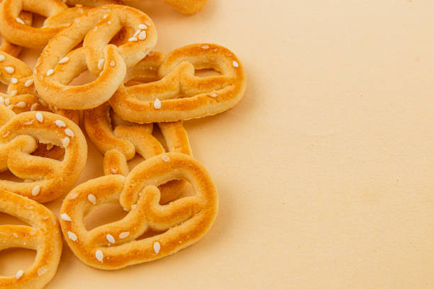 Crispy pretzels scattered on a light background with sesame seeds