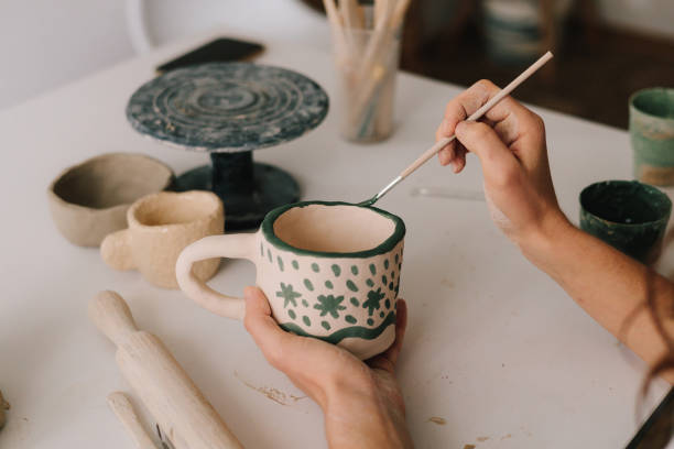 istock Design earthenware cup with a traditional pattern. Artist is making decoration on the clay ceramic mug after oven firing. 2199138815