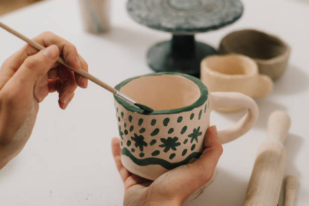 istock Design earthenware cup with a traditional pattern. Artist is making decoration on the clay ceramic mug after oven firing. 2199138913