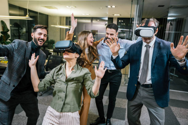 istock Group of business professionals standing and having fun in a modern office while wearing VR headsets 2199139566