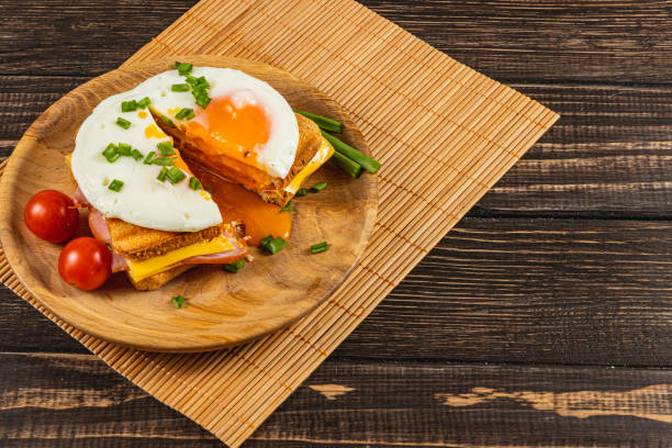 istock Delicious breakfast sandwich with fried egg and fresh tomatoes on wooden table 2199144451