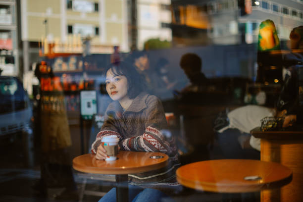 Portrait of a Japanese woman in a cafe, having a coffee break in Tokyo, after work or just spending a relaxing afternoon. Coffee, lifestyle concepts in Japan.