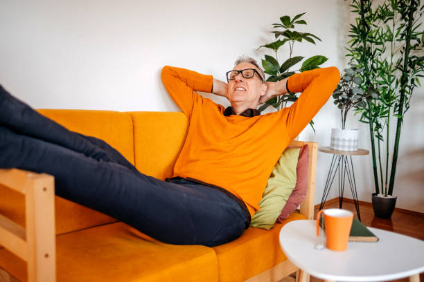 istock Mature adult spending time enjoying at home alone lying on sofa bed 2199149675