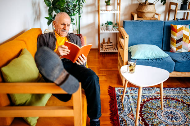 istock Senior adult spending time enjoying at home alone reading book 2199150123