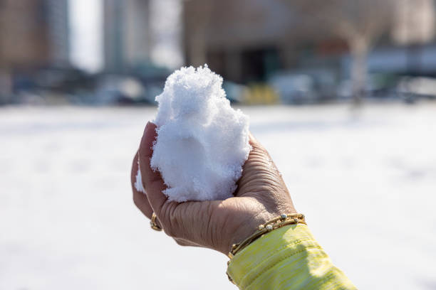 Woman in knitted mittens holding snowball outdoors, closeup