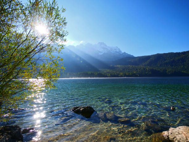 The crystal clear water of the Eibsee reflects the sun beams