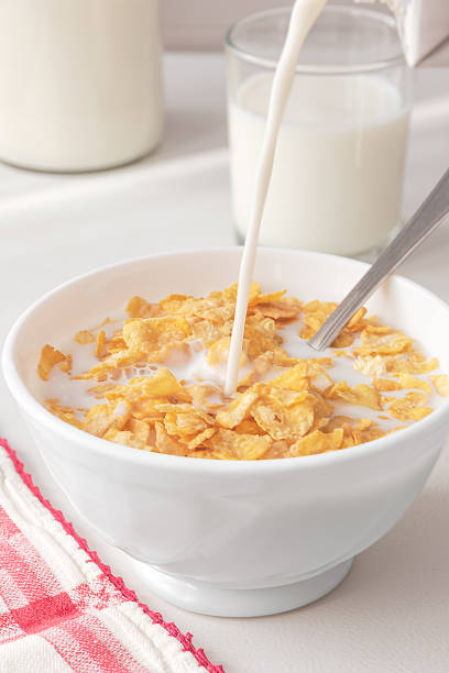 istock Filling a white bowl with milk with cereal on a white kitchen table. 2199164143