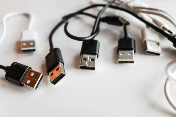Close-up of USB cable on reflective surface with out-of-focus computer mouse in background, staged for tech and office-related themes