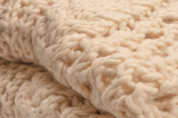 istock A fragment of beige knitted fabric, knitted from white sheep wool. 2199172417