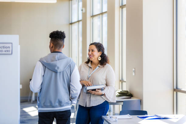istock Teacher and Student Discussing in Bright School Hallway 2199176532