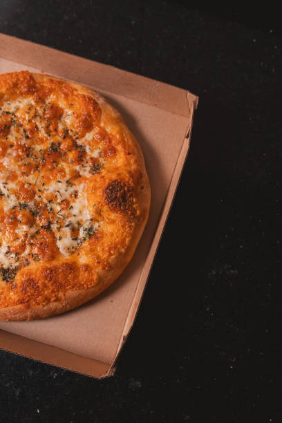 istock Overhead view of half of a mozzarella pizza on a cardboard box ready for delivery. 2199176800