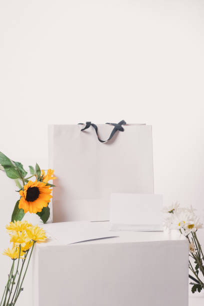 istock Bag with gift card and a sunflower with different flowers on a white background. 2199177092