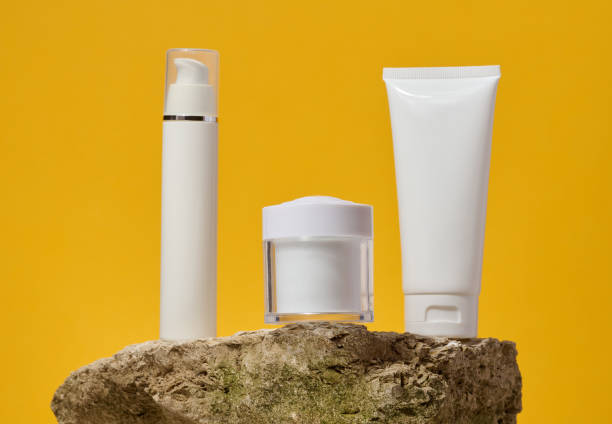 istock White plastic jars, tube stand on a stone on a yellow background. Container for cosmetics, cream 2199178358