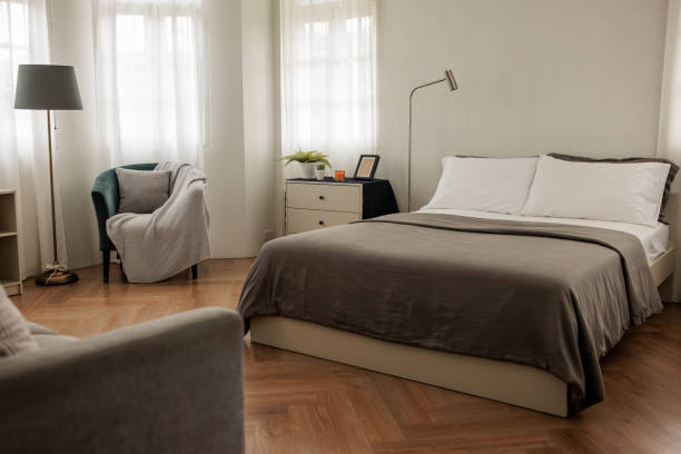 Well-designed bedroom featuring a comfortable bed with a grey bedspread and white pillows. The minimalistic decor and soft color palette create a soothing and inviting space.