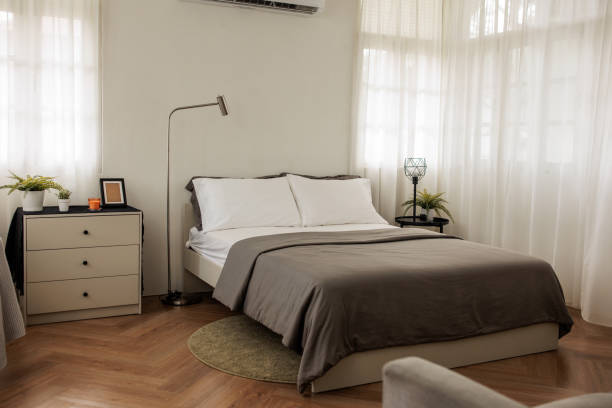 Well-designed bedroom featuring a comfortable bed with a grey bedspread and white pillows. The minimalistic decor and soft color palette create a soothing and inviting space.