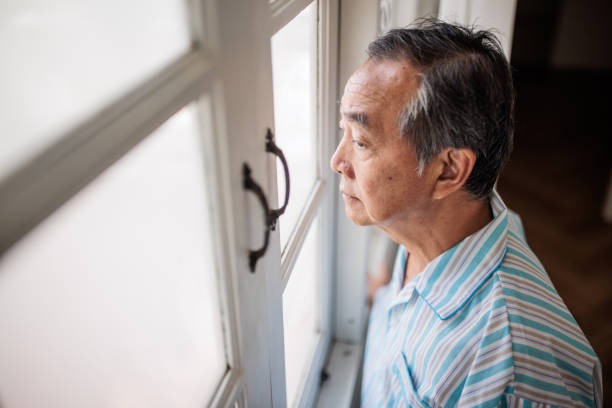 istock Senior Thai Man in Pajamas Looking Outside 2199182873