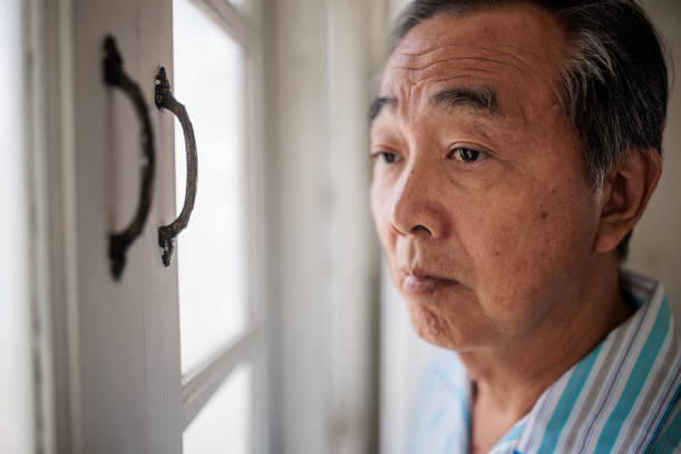 istock Senior Thai Man in Pajamas Looking Outside 2199182927