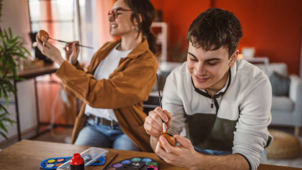 istock man paint decorative easter egg in living room while woman help him 2199210936