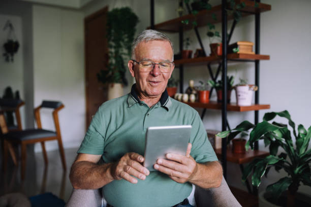 Senior man using a digital tablet in the living room