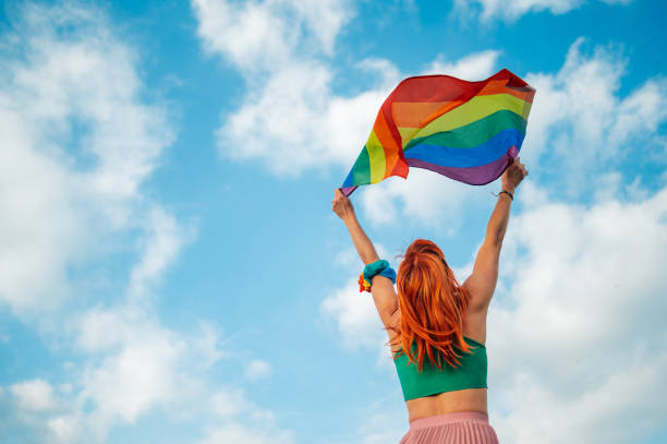 istock Woman holding rainbow flag celebrating pride with blue sky background 2199248409