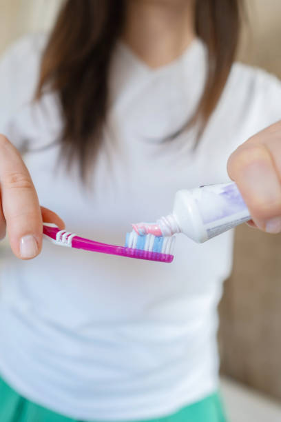 istock Woman's hands gently squeeze toothpaste onto the toothbrush before brushing her teeth. 2199248674