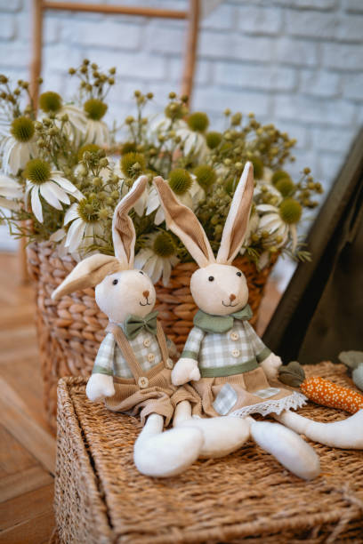 istock Handmade toy rabbits surrounded by flowers in a cozy indoor setting 2199248982