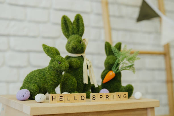 istock Spring decoration featuring moss bunnies and festive text on a wooden surface 2199249072