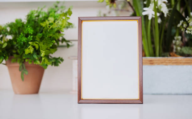 istock Blank wooden frame placed on a table near indoor plants in a modern space 2199249240