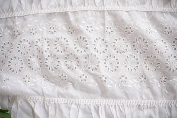 Detailed white fabric with embroidery featuring floral motifs and elegant ruffles.