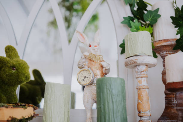 istock A whimsical rabbit figurine holds a clock near decorative candles and greenery 2199249340