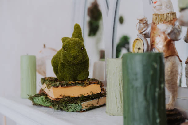 istock Green moss bunny sits on a stack of vintage books with candles nearby 2199249507