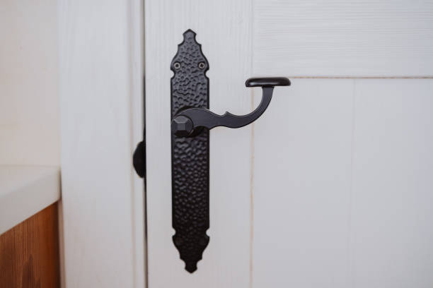 istock Decorative black door handle with intricate design on a white door 2199249587