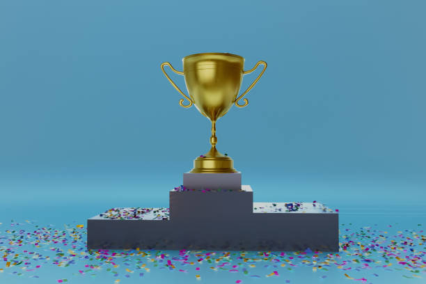 istock A gold cup is on top of a podium with confetti around it 2199271943
