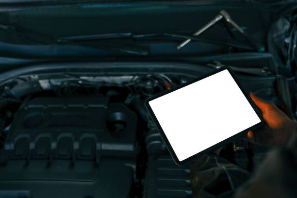 istock A tablet with a blank screen held by a mechanic above a car engine, symbolizing modern diagnostic tools for vehicle maintenance and repair. The engine is visible in the background 2199272095
