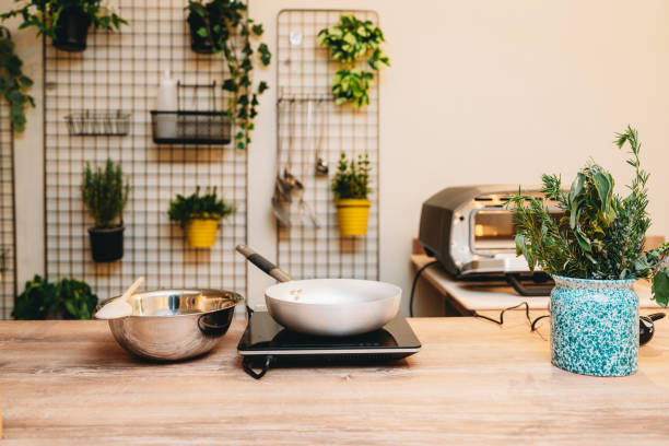 Modern and cozy kitchen space ready for cooking, featuring a frying pan on an induction cooker, a mixing bowl, and fresh herbs
