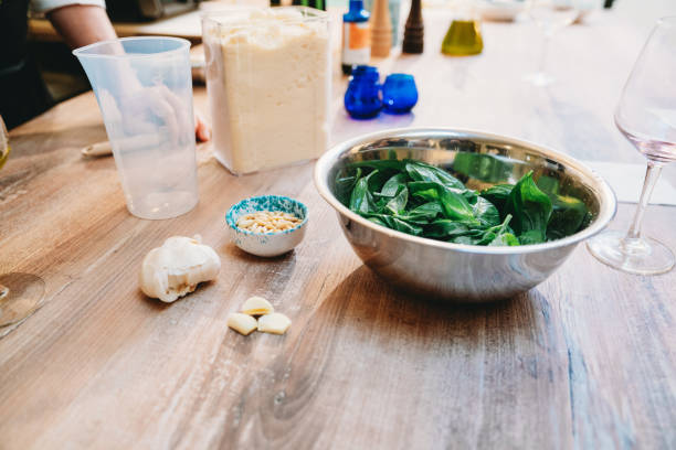 Fresh basil leaves, garlic, pine nuts and other ingredients are arranged on a wooden table, ready to be blended into a vibrant pesto sauce