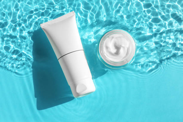 istock Tube and jar with moisturizing cream in water on light blue background, top view 2199276442