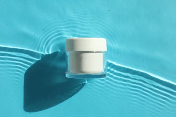 istock Jar with moisturizing cream in water on light blue background, top view 2199276446