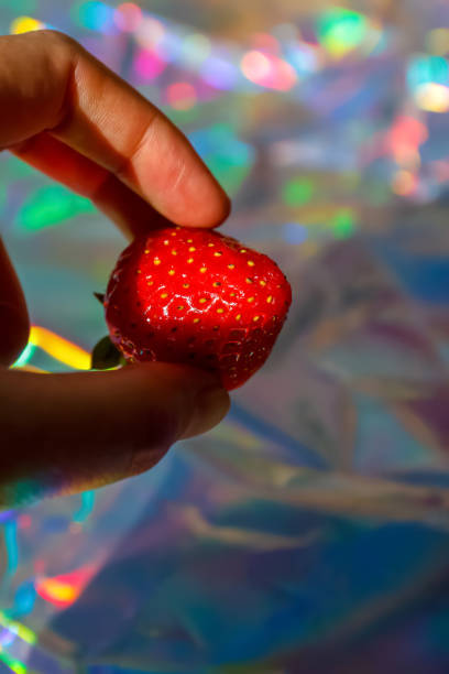 Fresh ripe strawberry in hand, holding a single strawberry, colorful strawberry on a modern background