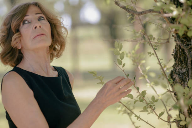 istock Senior woman touching leaves on tree branch 2199278597