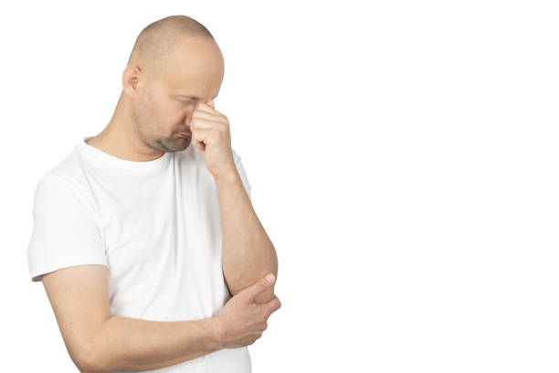 Pensive man in white t-shirt rubbing his forehead in stress