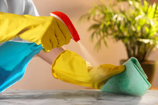 istock Woman with spray bottle and microfiber cloth cleaning white marble table at home, closeup 2199279152